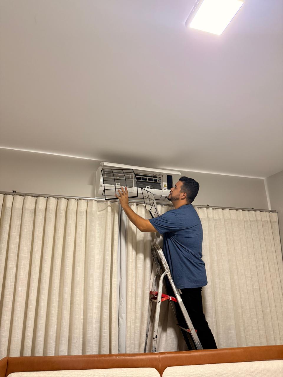 Técnico da Clima Pontes limpando o filtro de um split em apartamento de São Paulo